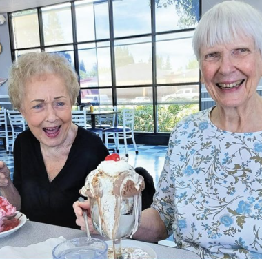 two women sitting at a table with food