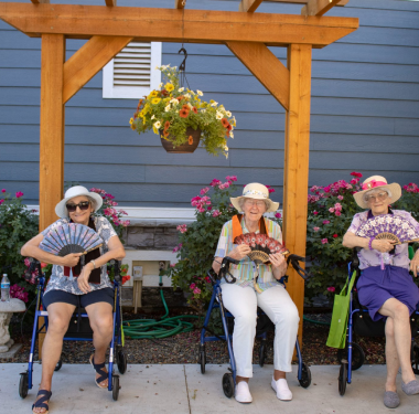 a group of women sitting in wheelchairs holding fans