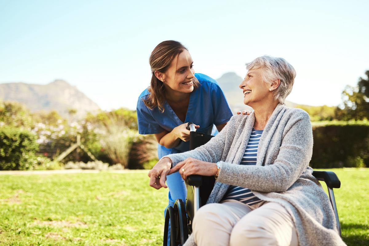 a nurse smiling at a person in a wheelchair